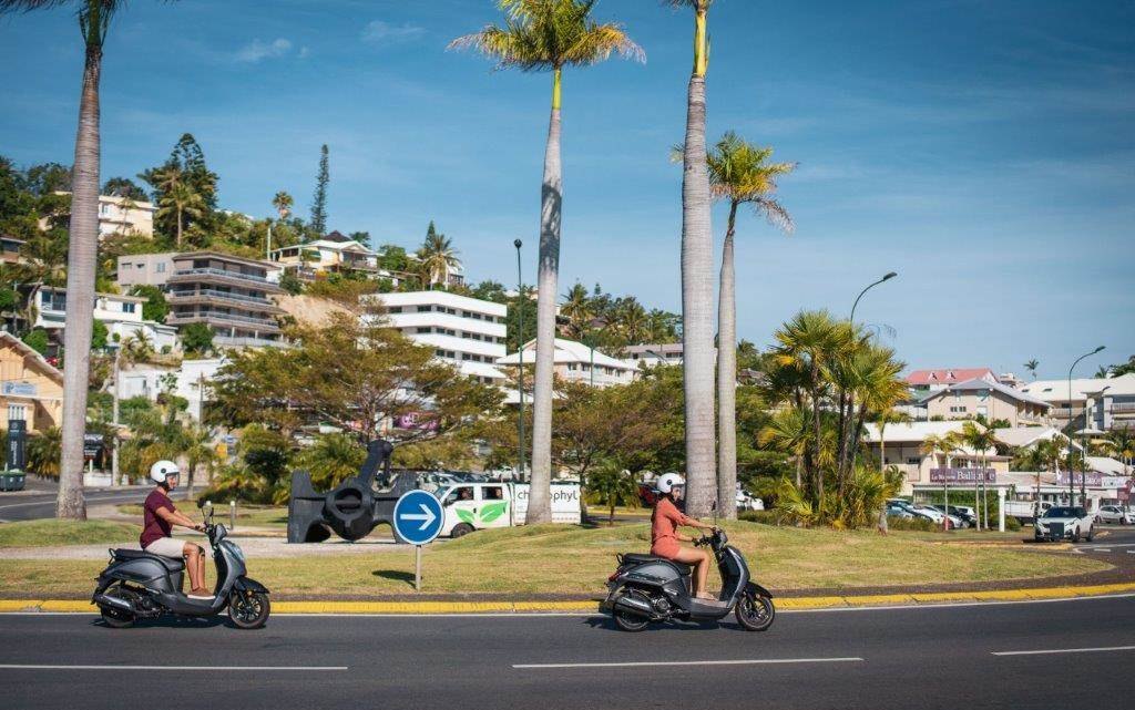 Deux scooters de location sur une avenue de Nouméa bordée de palmiers